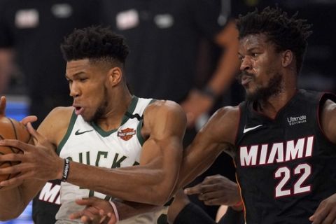 Milwaukee Bucks' Giannis Antetokounmpo, left, and Miami Heat's Jimmy Butler, right, compete for a rebound during the first half of an NBA basketball conference semifinal playoff game, Monday, Aug. 31, 2020, in Lake Buena Vista, Fla. (AP Photo/Mark J. Terrill)