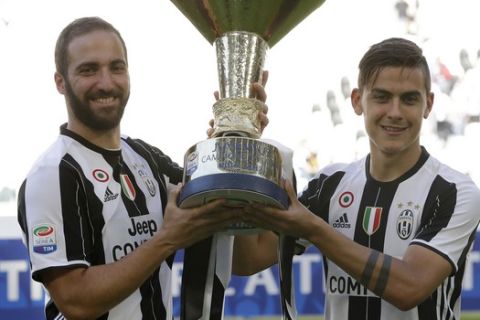 Juventus' Gonzalo Higuain, left, and Juventus' Paulo Dybala hold the trophy as Juventus players celebrate winning an unprecedented sixth consecutive Italian title, at the end of the Serie A soccer match between Juventus and Crotone at the Juventus stadium, in Turin, Italy, Sunday, May 21, 2017. (AP Photo/Antonio Calanni)