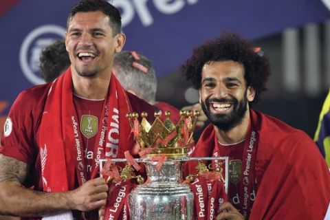 Liverpool's Dejan Lovren and Liverpool's Mohamed Salah celebrate with the English Premier League trophy aloft after it was presented following the Premier League soccer match between Liverpool and Chelsea at Anfield stadium in Liverpool, England, Wednesday, July 22, 2020. (Paul Ellis, Pool via AP)