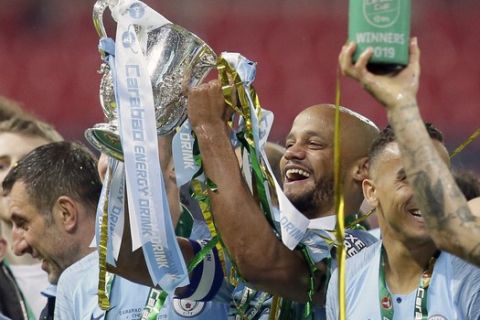 Manchester City's Vincent Kompany lifts the trophy after winning the English League Cup Final soccer match between Chelsea and Manchester City at Wembley stadium in London, England, Sunday, Feb. 24, 2019. (AP Photo/Tim Ireland)