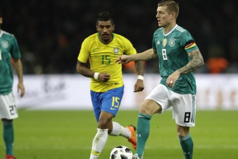 Germany's Toni Kroos, left, is challenged by Brazil's Paulinho, center, during the international friendly soccer match between Germany and Brazil in Berlin, Germany, Tuesday, March 27, 2018. (AP Photo/Michael Sohn)