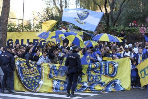 Police officers watch Boca Juniors supporters gathered outside the team hotel in Madrid Saturday, Dec. 8, 2018. The Copa Libertadores Final between River Plate and Boca Juniors will be played on Dec. 9 in Madrid, Spain, at Real Madrid's stadium. (AP Photo/Andrea Comas)