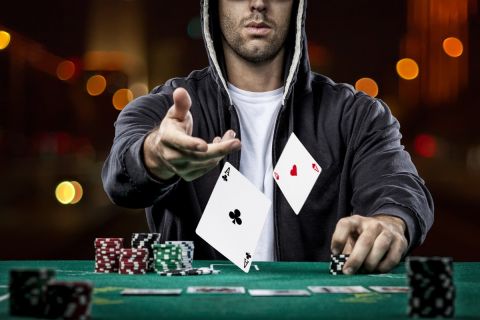 Poker player showing a pair of aces, on a bokeh lights background.