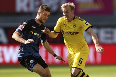 Paderborn's Dennis Srbeny, left, and Dortmund's Julian Brandt challenge for the ball during the German Bundesliga soccer match between SC Paderborn 07 and Borussia Dortmund at Benteler Arena in Paderborn, Germany, Sunday, May 31, 2020. Because of the coronavirus outbreak all soccer matches of the German Bundesliga take place without spectators. (Lars Baron/Pool via AP)