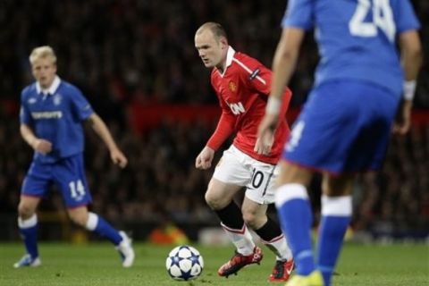 Manchester United's Wayne Rooney, center, runs at Rangers' Madjid Bougherra, right, during the first leg of their Group C Champions League soccer match, Old Trafford, Manchester, England, Tuesday Sept. 14, 2010. (AP Photo/Jon Super)