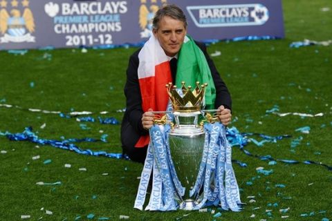 Manchester City's Italian manager Roberto Mancini celebrates with the Premier League trophy on the pitch after their 3-2 victory over Queens Park Rangers in the English Premier League football match between Manchester City and Queens Park Rangers at The Etihad stadium in Manchester, north-west England on May 13, 2012. Manchester City won the game 3-2 to secure their first title since 1968. This is the first time that the Premier league title has been decided on goal-difference, Manchester City and Manchester United both finishing on 89 points. AFP PHOTO/PAUL ELLIS

RESTRICTED TO EDITORIAL USE. No use with unauthorized audio, video, data, fixture lists, club/league logos or 'live' services. Online in-match use limited to 45 images, no video emulation. No use in betting, games or single club/league/player publications.        (Photo credit should read PAUL ELLIS/AFP/GettyImages)