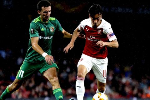 Arsenal's Mesut Ozil, right, and Vorskla's Vyacheslav Sharpar challenge for the ball during the Europa League Group E soccer match between Arsenal and Vorskla in London, England, Thursday, Sept. 20, 2018. (AP Photo/Kirsty Wigglesworth)