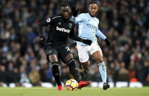 West Ham United's Arthur Masuaku, left, and Manchester City's Raheem Sterling  battle for the ball during the English Premier League soccer match at the Etihad Stadium, Manchester, England, Sunday, Dec. 3, 2017. (Martin Rickett/PA via AP)