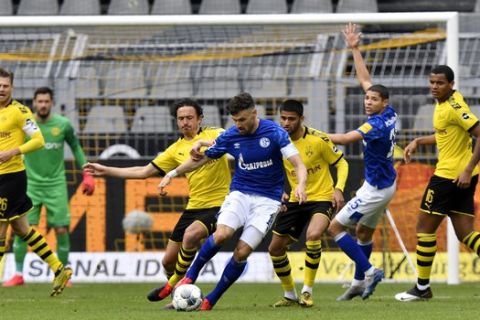 Dortmund's Thomas Delaney, center right, fights for the ball with Schalke's Daniel Caligiuri during the German Bundesliga soccer match between Borussia Dortmund and Schalke 04 in Dortmund, Germany, Saturday, May 16, 2020. The German Bundesliga becomes the world's first major soccer league to resume after a two-month suspension because of the coronavirus pandemic. (AP Photo/Martin Meissner, Pool)