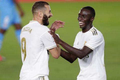 Real Madrid's Karim Benzema, left, smiles with his teammate Ferland Mendy after scoring his side's third goal during the Spanish La Liga soccer match between Real Madrid and Valencia at Alfredo di Stefano stadium in Madrid, Spain, Thursday, June 18, 2020. (AP Photo/Manu Fernandez)