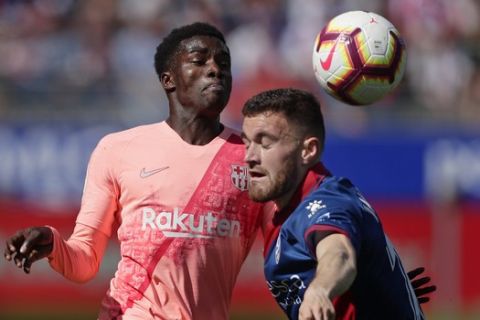 Barcelona's Moussa Wague, left, vies for a ball with Huesca's Javi Galan during the Spanish La Liga soccer match between Huesca and Barcelona at the Alcoraz stadium in Huesca, Saturday, April 13, 2019. (AP Photo/Manu Fernandez)