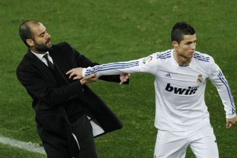 Barcelona's coach Josep Guardiola, left is pushed by Real Madrid's Cristiano Ronaldo from Portugal, right, during their La Liga soccer match at the Camp Nou stadium, in Barcelona, Monday, Nov. 29, 2010. Ronaldo was given a yellow card for the offence. (AP Photo/Daniel Ochoa de Olza)