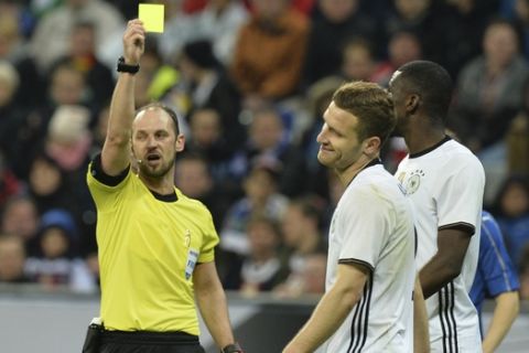 Referee Oliver Drachta, left, books Germanys Shkodran Mustafi, center, during a friendly soccer match between Germany and Italy at the Allianz Arena in Munich, southern Germany, Tuesday, March 29, 2016. (AP Photo/Kerstin Joensson)