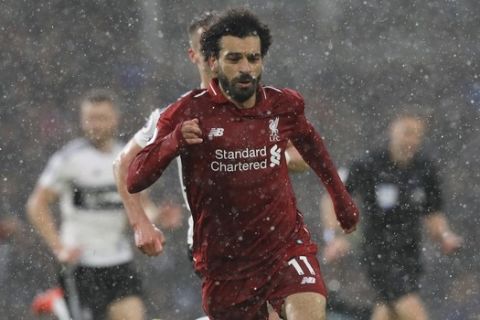 Liverpool's Mohamed Salah runs with the ball under pouring rain, during the English Premier League soccer match between Fulham and Liverpool at Craven Cottage stadium in London, Sunday, March 17, 2019. (AP Photo/Kirsty Wigglesworth)