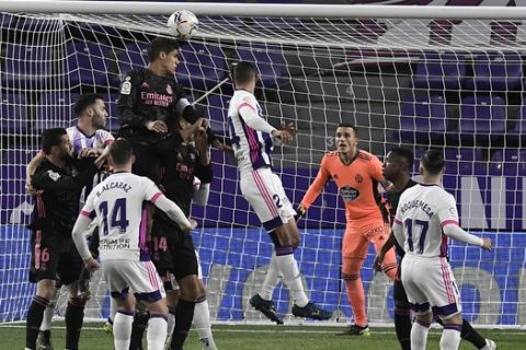 Real Madrid's Raphael Varane, top left, attempts a head at goal in front of Valladolid's goalkeeper Jordi Masip, background, during the Spanish La Liga soccer match between Valladolid and Real Madrid at the Jose Zorrila stadium in Valladolid, Spain, Saturday, Feb. 20, 2021. (AP Photo/Alvaro Barrientos)
