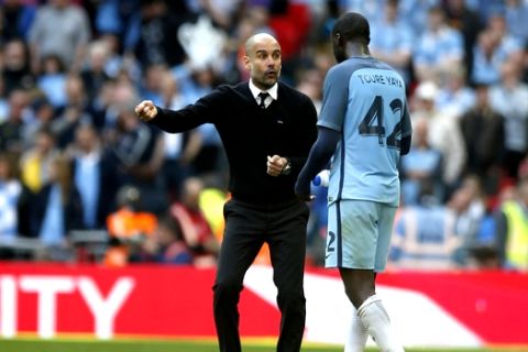 Manchester City manager Pep Guardiola, left, talks to Manchester City's Yaya Toure during the English FA Cup semifinal soccer match between Arsenal and Manchester City at Wembley stadium in London, Sunday, April 23, 2017. (AP Photo/Alastair Grant)