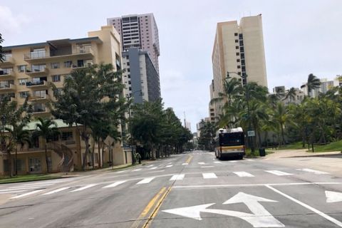A city bus is parked on an empty street in the Waikiki neighborhood of Honolulu, Thursday, March 26, 2020. A 14-day quarantine on travelers takes effect in Hawaii, one of the world's most famous tourist destinations, as the island state fights the coronavirus. Hawaii welcomed 10 million travelers last year, for an average of about 830,000 a month. Authorities expect this number will dwindle to nearly zero in April as the new rule is implemented. Dozens of hotels are temporarily shutting their doors in response. (AP Photo/Caleb Jones)