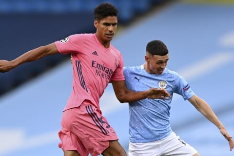 Real Madrid's Raphael Varane, left, is challenged by Manchester City's Phil Foden during the Champions League round of 16, second leg soccer match between Manchester City and Real Madrid at the Etihad Stadium stadium in Manchester, England, Friday, Aug. 7, 2020. (Shaun Botterill, Pool via AP)