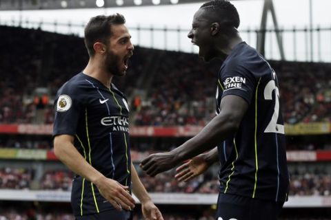 Manchester City's Bernardo Silva celebrates with teammate Benjamin Mendy, right, after scoring his side's second goal during the English Premier League soccer match between Arsenal and Manchester City at the Emirates stadium in London, England, Sunday, Aug. 12, 2018. (AP Photo/Tim Ireland)