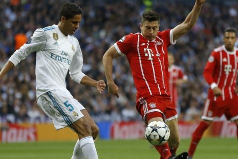 Real Madrid's Raphael Varene, left, and Bayern's Robert Lewandowski challenge for the ball during the Champions League semifinal second leg soccer match between Real Madrid and FC Bayern Munich at the Santiago Bernabeu stadium in Madrid, Spain, Tuesday, May 1, 2018. (AP Photo/Francisco Seco)