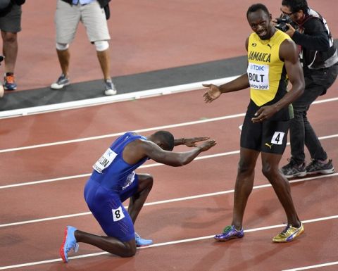 United States' Justin Gatlin, left, bows as he celebrates his win in the Men's 100 meters final as third placed Jamaica's Usain Bolt watches during the World Athletics Championships in London Saturday, Aug. 5, 2017. (AP Photo/Martin Meissner)