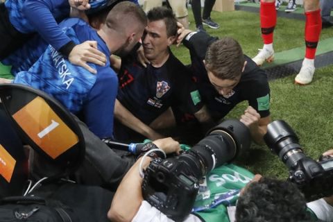 Croatia's Mario Mandzukic, sits on the ground after he fell over a photographer when celebrating his side's second goal during the semifinal match between Croatia and England at the 2018 soccer World Cup in the Luzhniki Stadium in Moscow, Russia, Wednesday, July 11, 2018. (AP Photo/Frank Augstein)