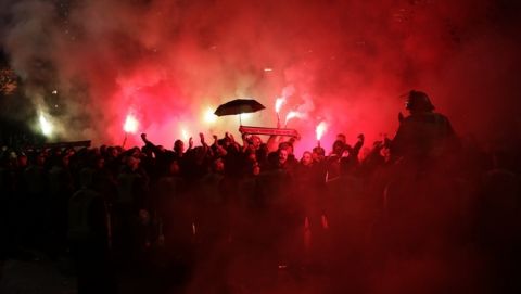 Eintracht Frankfurt fans, who are not allowed in the stadium after crowd trouble at their game against Vitoria Guimaraes in October, let off flares as their team's bus with the players arrives for the Europa League Group F soccer match between Arsenal and Eintracht Frankfurt at the Emirates Stadium, in London, Thursday, Nov. 28, 2019. (AP Photo/Matt Dunham)