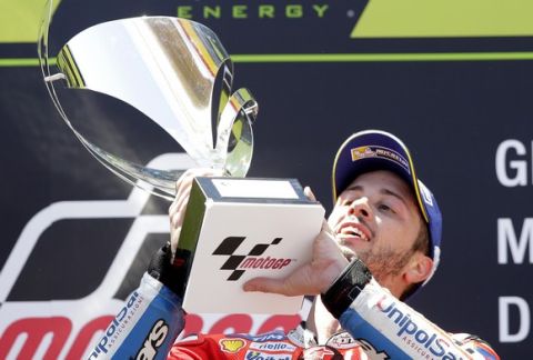 Moto GP rider Andrea Dovizioso of Italy lifts his trophy on the podium after winning the Catalunya Motorcycle Grand Prix at the Barcelona Catalunya racetrack in Montmelo, just outside Barcelona, Spain, Sunday, June 11, 2017. (AP Photo/Manu Fernandez)