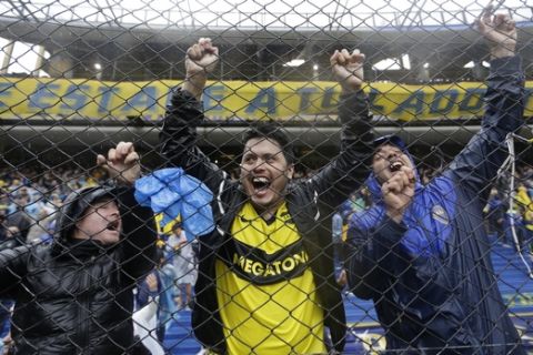 Fans of Argentina's Boca Junior cheer under the rain at the stands of the Alberto Armando stadium in Buenos Aires, Argentina Saturday, Nov. 10, 2018. The South American Football Confederation suspended the first leg of the Copa Libertadores final between Argentina's two biggest teams, Boca Juniors and River Plate, because torrential rain flooded the stadium. (AP Photo/Natacha Pisarenko)