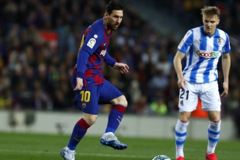 Barcelona's Lionel Messi, left, plays the ball past Real Sociedad's Martin Oedegaard during a Spanish La Liga soccer match between Barcelona and Real Sociedad at the Camp Nou stadium in Barcelona, Spain, Saturday, March 7, 2020. (AP Photo/Joan Monfort)