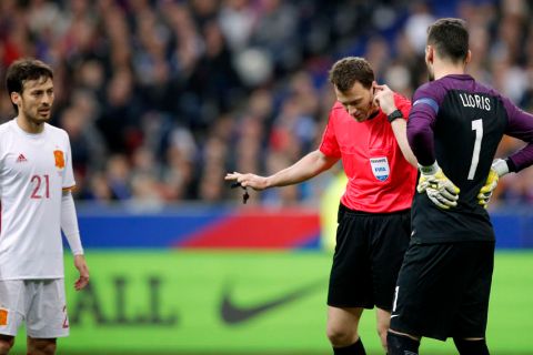 Spain's scorer David Silva, left, looks on as Referee Felix Zwayer, center, from Germany holds his earphone during the international friendly soccer match between France and Spain at the Stade de France in Paris, France, Tuesday, March 28, 2017. At right is France's goalkeeper Hugo Lloris. (AP Photo/Christophe Ena)