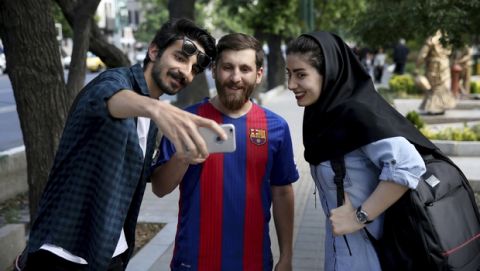 In this Monday, May 8, 2017 photo, two Iranians take a selfie with Reza Parastesh, Iranian doppelganger, or look-alike, of Lionel Messi, Argentinian soccer legend in Tehran, Iran. (AP Photo/Ebrahim Noroozi)