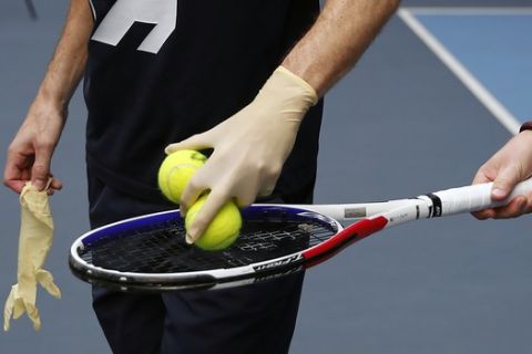 French veteran Nicolas Mahut, wearing protective gloves, participates at a training session in the French Tennis Federation center near the grounds of the French Open in Paris, Wednesday, May 13, 2020 under the watchful eye of a team doctor and courtside trainers. Professional tennis players resumed training in France after the end of lockdown amid the coronavirus pandemic. (AP Photo/Francois Mori)