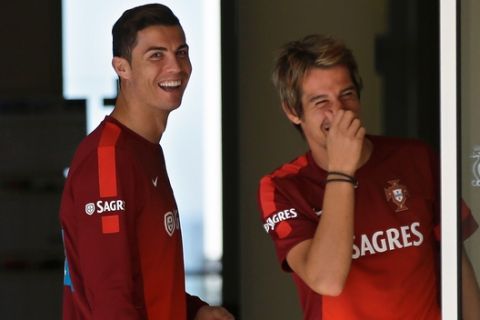 Portugal's Cristiano Ronaldo, left, and Fabio Coentrao joke with teammate Pepe who was giving a news conference after a training session, near Obidos, Portugal, Wednesday, Nov. 13 3013. Friday the Portuguese soccer team will face Sweden in a qualifying play-off match for the 2014 World Cup. Ronaldo joined his teammates on the pitch after two days training separately recovering from an injury on his left foot. (AP Photo/Armando Franca)