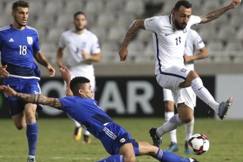 Cyprus' Fanos Katelaris, left, battles for the ball with Greece's Kostas Mitroglou during their World Cup Group H qualifying soccer match between Cyprus and Greece at GSP stadium in Nicosia, Cyprus, Saturday, Oct. 7, 2017. (AP Photo/Petros Karadjias)