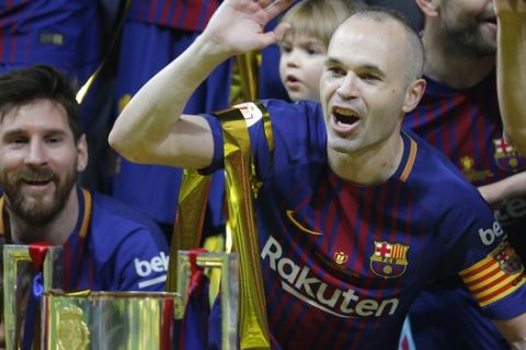 FC Barcelona's Andres Iniesta, right, and Lionel Messi celebrate during an award ceremony after defeating Sevilla 5-0 in the Copa del Rey final soccer match at the Wanda Metropolitano stadium in Madrid, Spain, Saturday, April 21, 2018. (AP Photo/Paul White)
