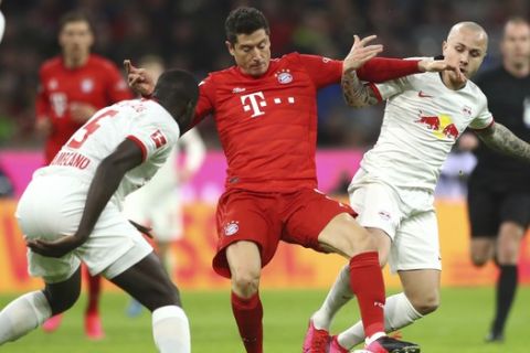 Bayern's Robert Lewandowski, centre, and Leipzig's Angelino, right, challenge for the ball during the German Bundesliga soccer match between Bayern Munich and RB Leipzig at the Allianz Arena in Munich, Germany, Sunday, Feb. 9, 2020. (AP Photo/Matthias Schrader)