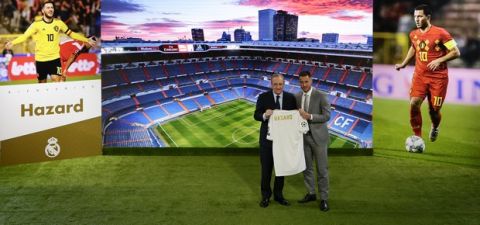 Belgium forward Eden Hazard, right, holds his new shirt with Real Madrid's President Florentino Perez during his official presentation after signing for Real Madrid at the Santiago Bernabeu stadium in Madrid, Spain, Thursday, June 13, 2019. Real Madrid announced last week that it had acquired the 28-year-old Belgian playmaker from Chelsea for a reported fee of around 100 million euros ($113 million) plus variables, making him the club's most expensive signing ever. (AP Photo/Manu Fernandez)