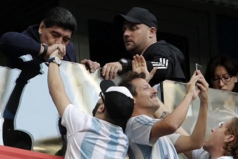 Argentina former soccer star Diego Maradona kisses the hand of a soccer fan ahead of the group D match between Argentina and Nigeria, at the 2018 soccer World Cup in the St. Petersburg Stadium in St. Petersburg, Russia, Tuesday, June 26, 2018. (AP Photo/Petr David Josek)