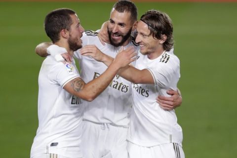 Real Madrid's Karim Benzema, center, celebrates with his teammates Eden Hazard, left, and Luka Modric after scoring his side's opening goal during the Spanish La Liga soccer match between Real Madrid and Valencia at Alfredo di Stefano stadium in Madrid, Spain, Thursday, June 18, 2020. (AP Photo/Manu Fernandez)