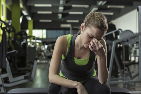 Young woman having headache after working out in a health club