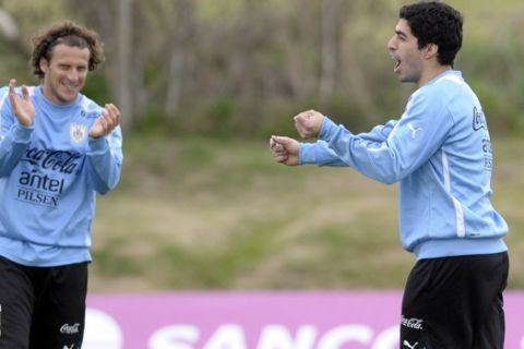 Uruguay's Diego Forlan, left, and Luis Suarez, right, attend a team training session on the outskirts of Montevideo, Tuesday, March 19, 2013. Uruguay will face Paraguay in a World Cup 2014 qualifying soccer game on March 22. (AP Photo/Matilde Campodonico)