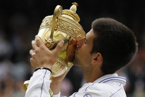 Serbia's Novak Djokovic kisses the trophy after defeating Spain's Rafael Nadal in the men's singles final at the All England Lawn Tennis Championships at Wimbledon, Sunday, July 3, 2011. (AP Photo/Kirsty Wigglesworth)