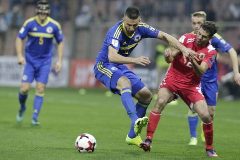 Bosnia's Vedad Ibisevic, left, in action with Gibraltar's Jan Carlos Garcia, during  their World Cup Group H qualifying match at the Bilino Polje Stadium in Zenica on Saturday, March 25, 2017. (AP Photo/Amel Emric)