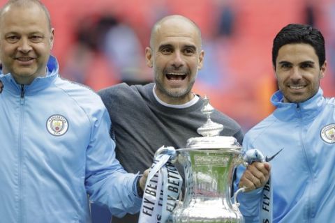 Manchester City's manager Pep Guardiola, center, celebrates with the trophy after the English FA Cup Final soccer match between Manchester City and Watford at Wembley stadium in London, Saturday, May 18, 2019. (AP Photo/Kirsty Wigglesworth)