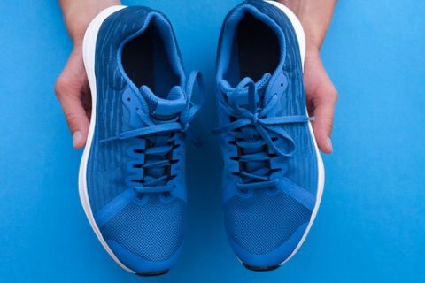 Hands holding a pair of new fitness sport sneakers. Buy a new shoes. Choosing of sneakers for running concept.