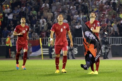 FILE - In this file photo dated Tuesday, Oct. 14, 2014, Serbia's Stefan Mitrovic grabs a banner containing the Albanian flag attached to a drone flying above the pitch during the Euro 2016 Group I qualifying match between Serbia and Albania in Belgrade, Serbia. The banner prompted fan violence with the match was suspended, and a man who claims to have flown the drone has been detained but it is revealed Saturday July 29, 2017, that Albanias soccer federation is calling on Albanian authorities to stop his extradition to Serbia. (AP Photo/Darko Vojinovic, FILE)