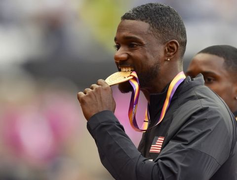 Gold medalist United States' Justin Gatlin, bites his medal following the medal ceremony for the Men's 100 meters at the World Athletics Championships in London Sunday, Aug. 6, 2017. (AP Photo/Martin Meissner)