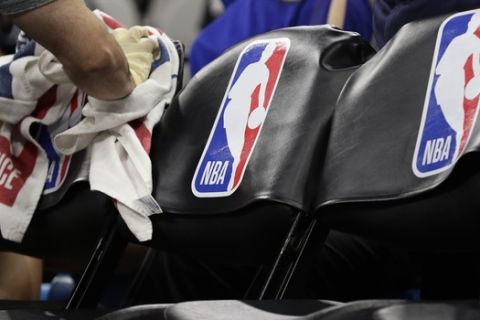 A team attendant uses protective gloves to wipe down seats in the players' bench area during an NBA basketball game between the San Antonio Spurs and the Dallas Mavericks in San Antonio, Tuesday, March 10, 2020. (AP Photo/Eric Gay)