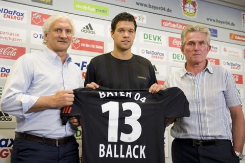 Germany's national soccer captain Michael Ballack holds up his football shirt as he stands between Bayer Leverkusen coach Jupp Heynckes (R) and manager Rudi Voeller (L) during a news conference in the western German city of Leverkusen July 14, 2010. The 33 year-old midfield player was presented by soccer club Bayer Leverkusen on Wednesday after signing from Chelsea. Ballack singed a contract with his former club, where he played between 1999 and 2002.   REUTERS/Kirsten Neumann    (GERMANY - Tags: SPORT SOCCER)
